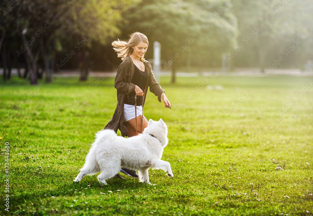 Pretty girl playing with samoyed dog during walk outdoor