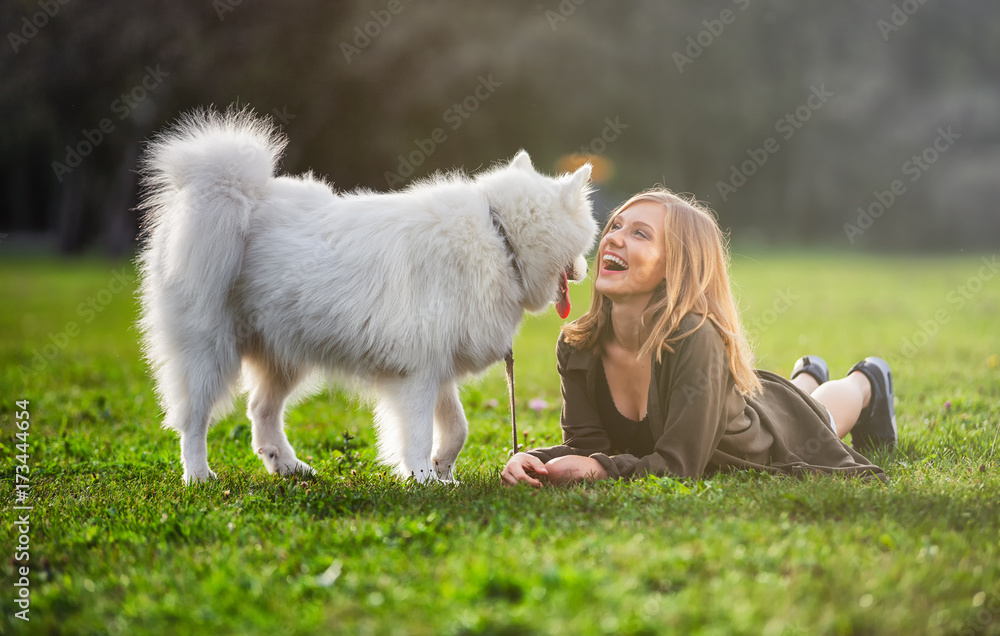 Pretty girl playing with dog on grass at the park