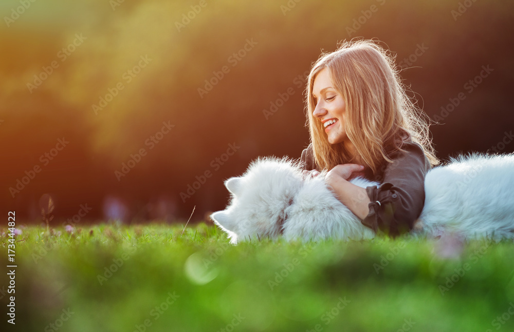 Pretty girl playing with dog on grass at the park