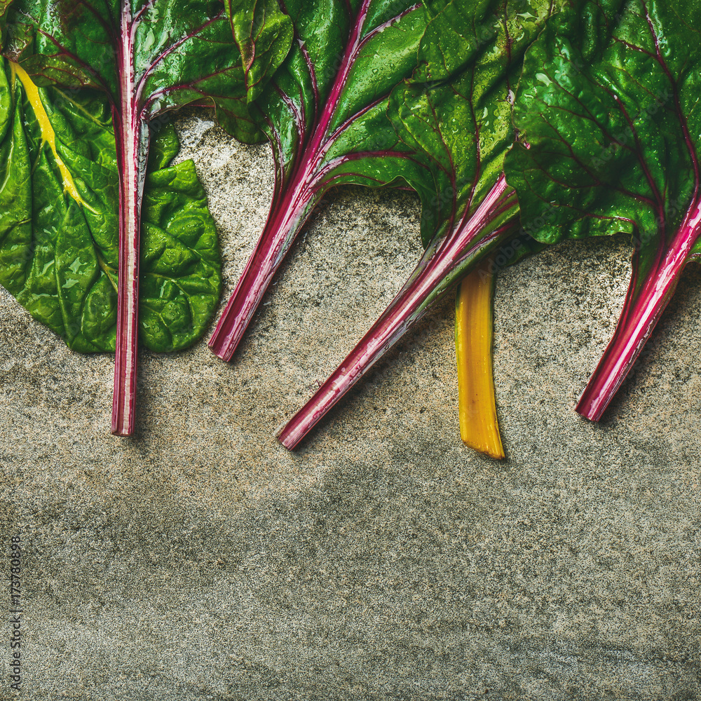 Flat-lay of fresh leaves of swiss chard over concrete stone background, copy space, top view, square