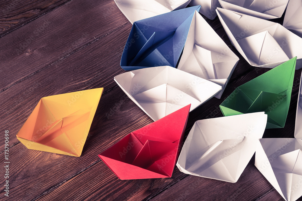 Business leadership concept with white and color paper boats on 