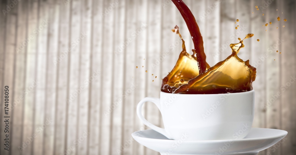 Coffee being poured into white cup against blurry wood panel