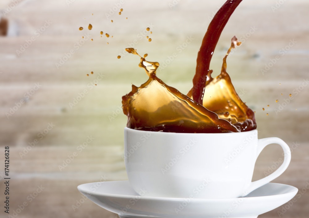 Coffee being poured into white cup against blurry wood panel