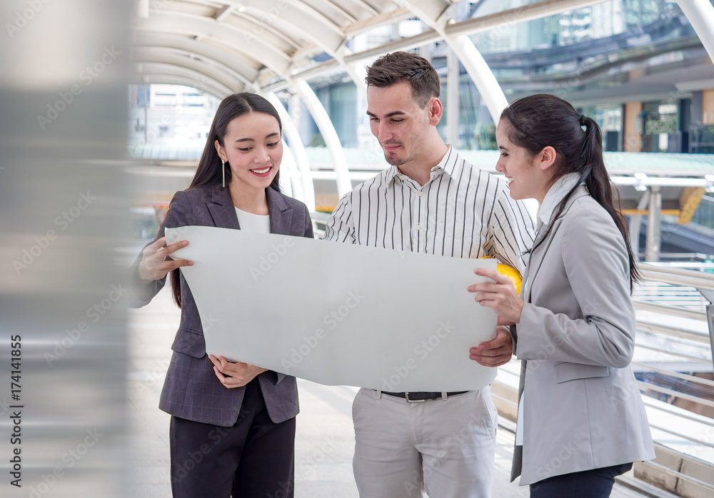 Young caucasian engineer/architect holding drawing/blueprint discuss with businesswoman for a projec