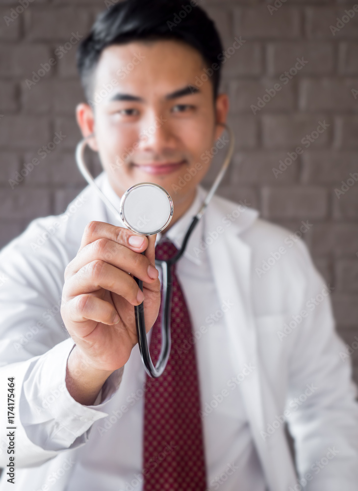 微笑的亚洲医生穿着制服拿着听诊器（特写）进行医学概念