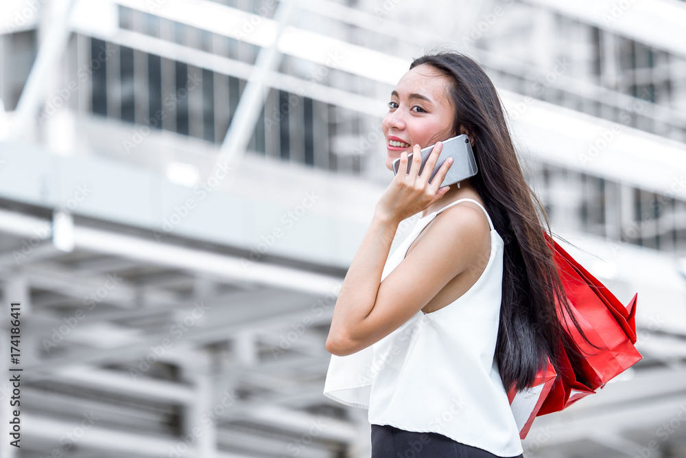 特写女人拿着购物袋，五颜六色地走在有复制空间的城市里