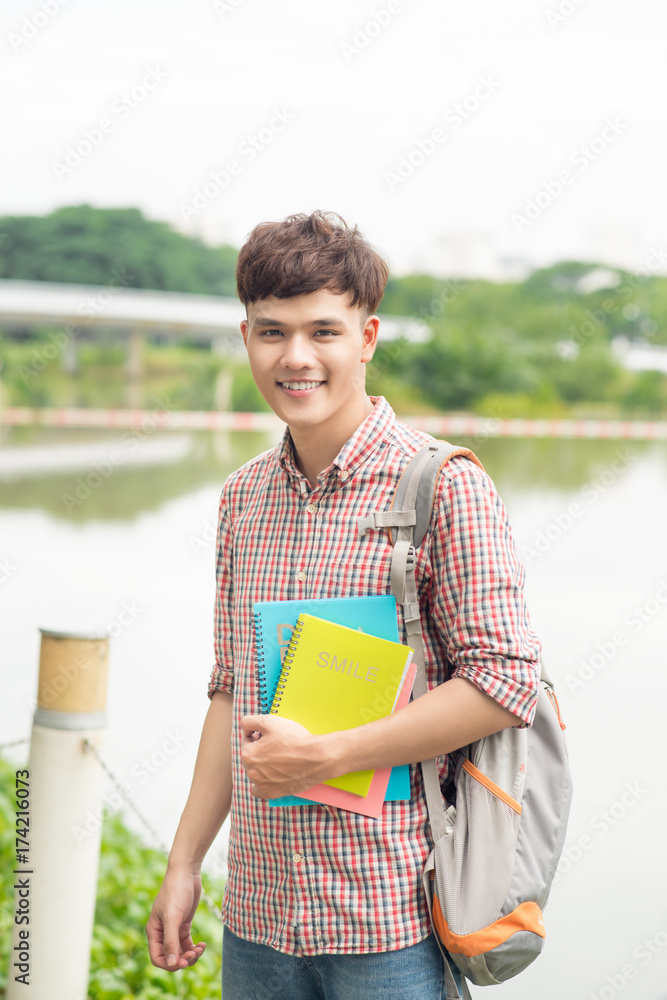 大学亚洲男学生在公园里拿着书