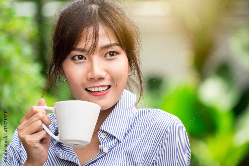 Young asian beautiful woman holding a cup of coffee in the morning;