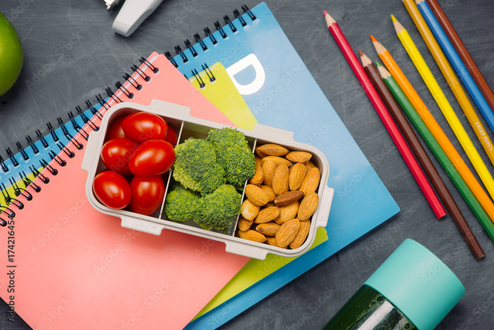 School breakfast on desk with books and pen on board background