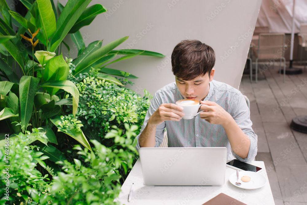 Young male freelancer working with laptop computer in comfortable coffee shop