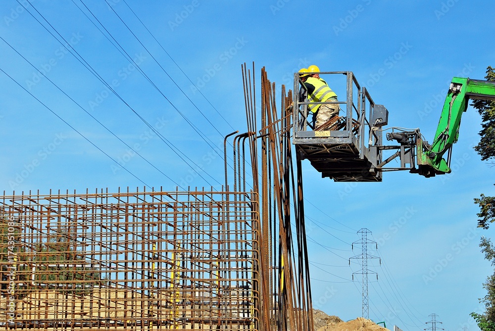 builder workers knitting metal rods bars into framework reinforcement for concrete pouring at constr