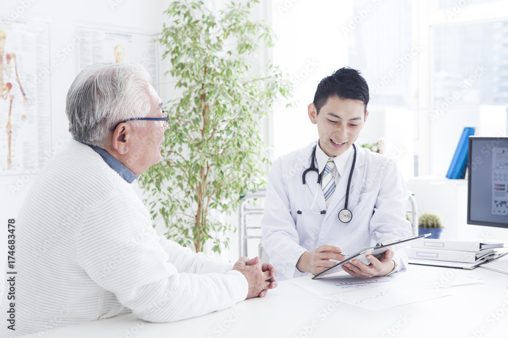 A young doctor is examining an old man in the hospotal