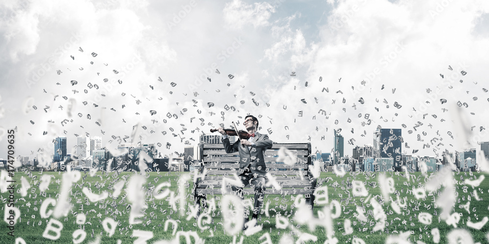 Handsome violinist in park on wooden bench and symbols fly aroun