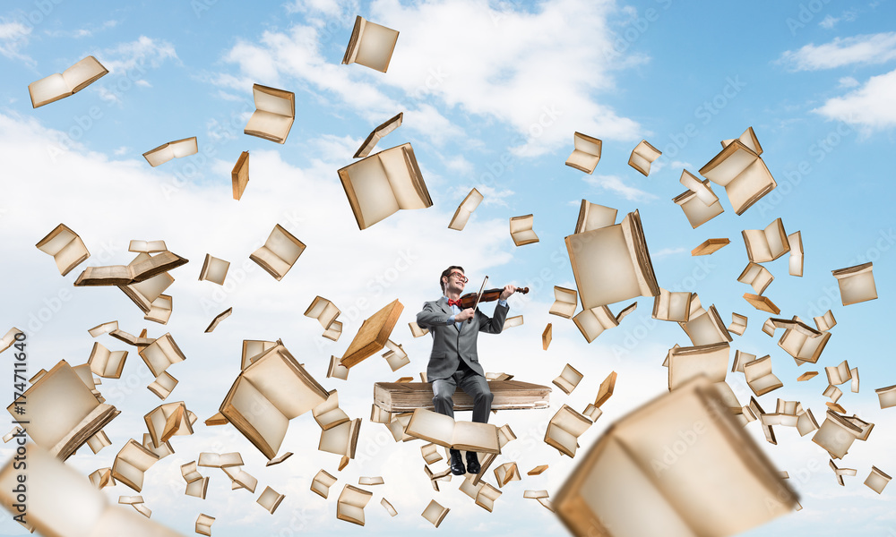 Handsome violinist sitting on book and play his melody