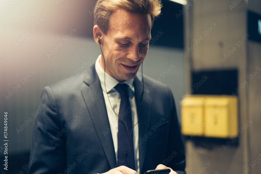 Businessman standing in a subway station reading text messages