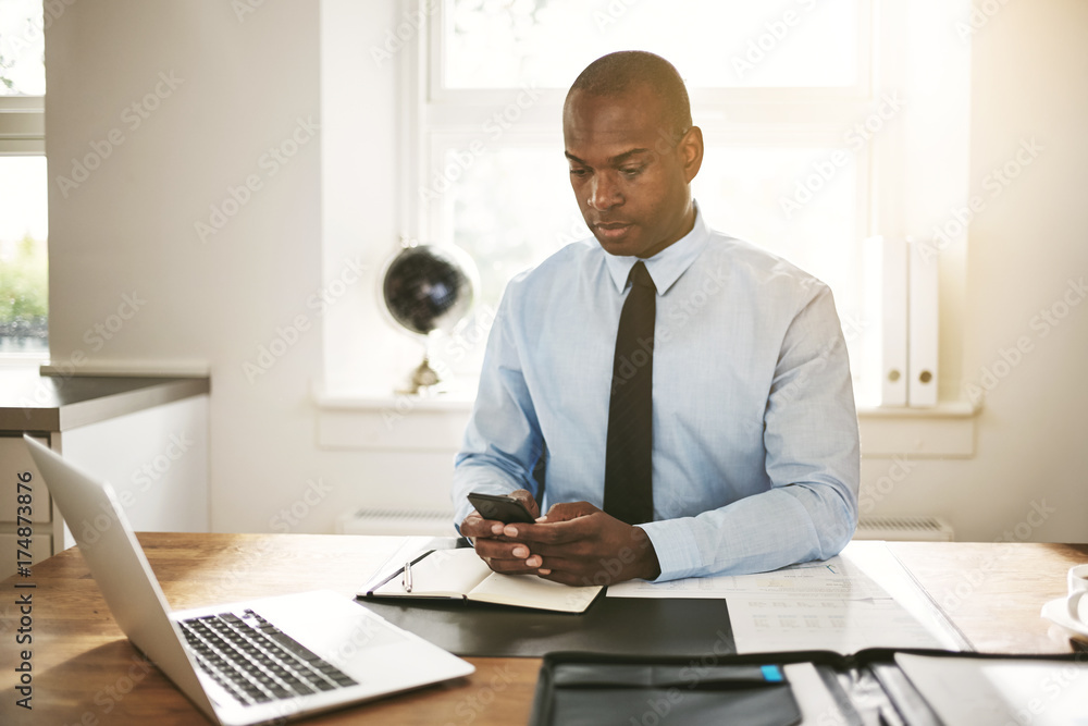 Young businessman reading text messages at his office desk