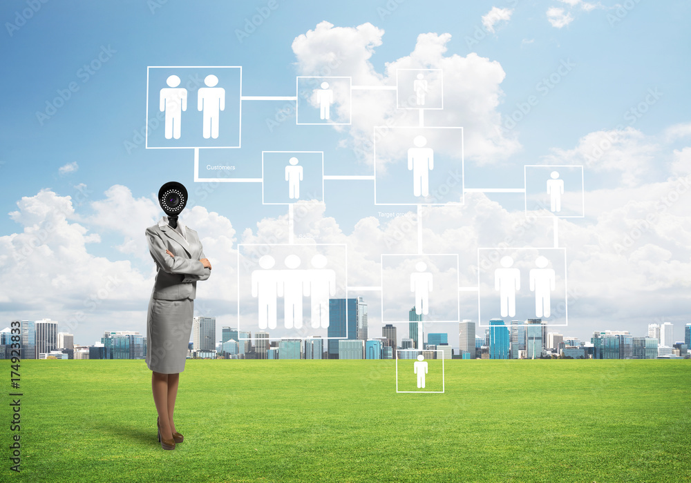 Camera headed woman standing on green grass against modern cityscape