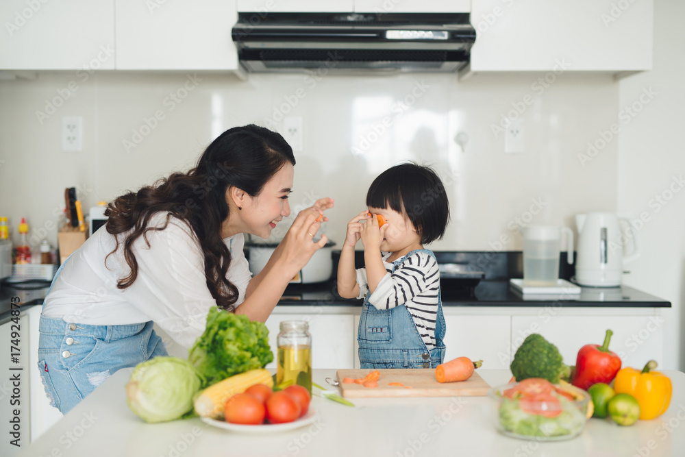 Happy family in the kitchen. Mother and child daughter are preparing the vegetables and fruit.