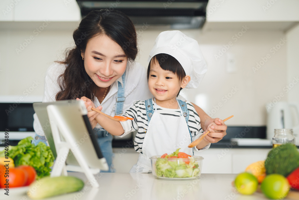 母亲和女儿在厨房准备午餐，一起享受。