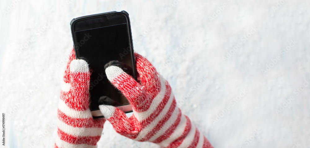 Hands using phone in winter gloves