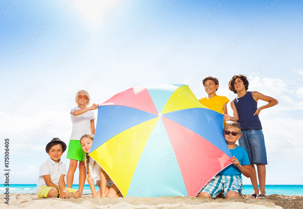 Many kids in large group behind beach umbrella