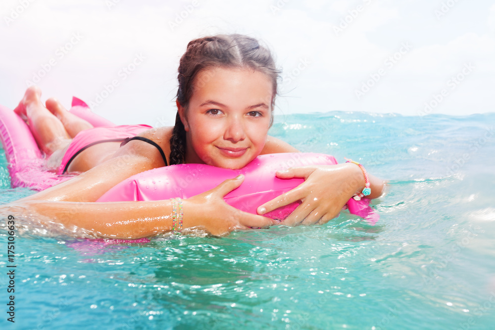 Cute teenage girl laying on matrass in sea