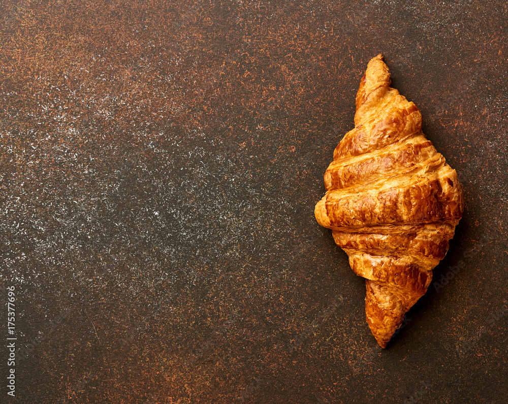 Croissant on brown concrete background. Bakery product. Copy space.