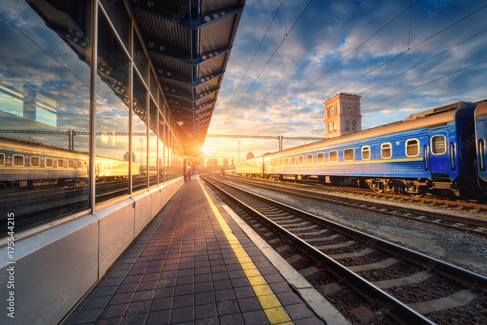 Beautiful train with blue wagons at the railway station at sunset. Industrial view with modern train