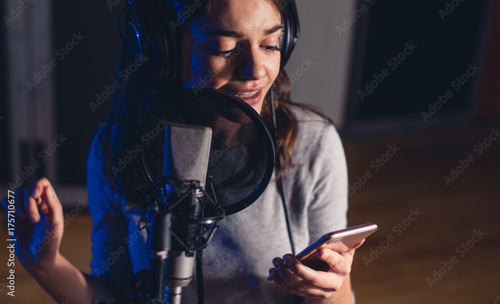 Singer singing in the recording studio with mobile phone