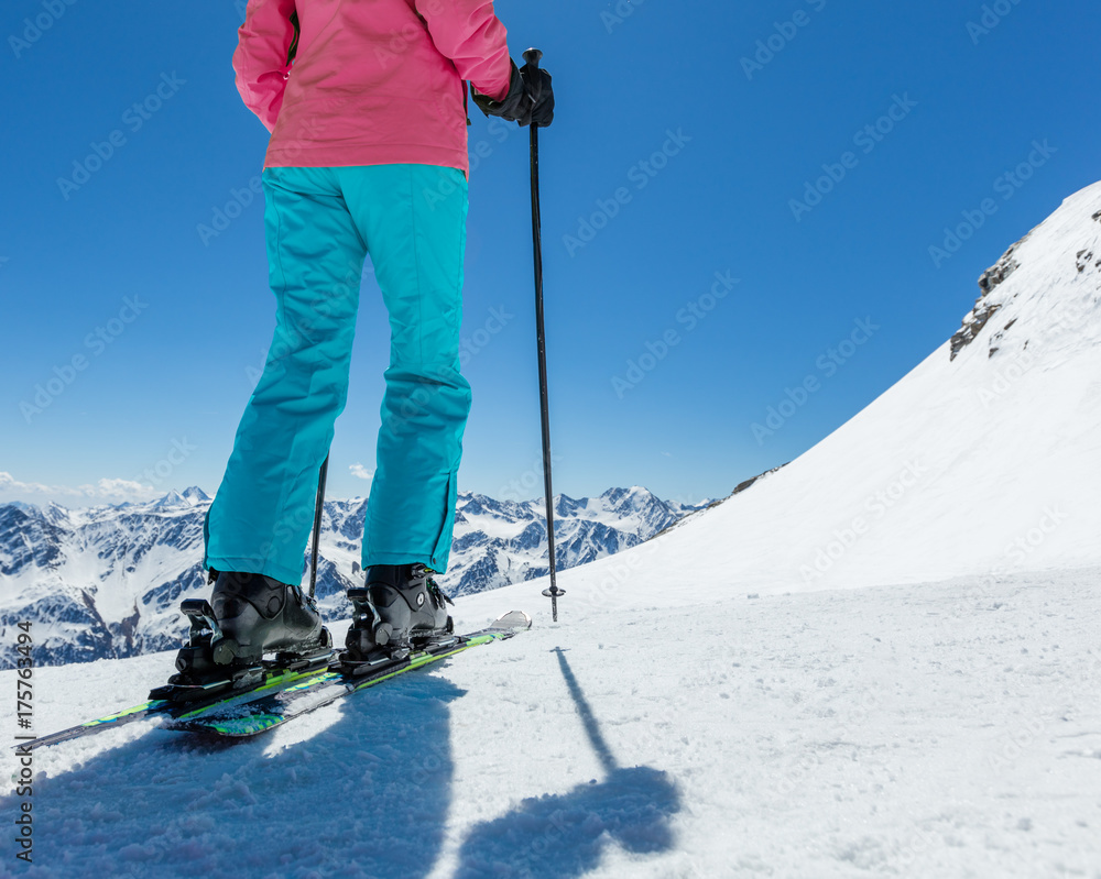 Detail of legs of young woman skier in beautiful Alpine landscape