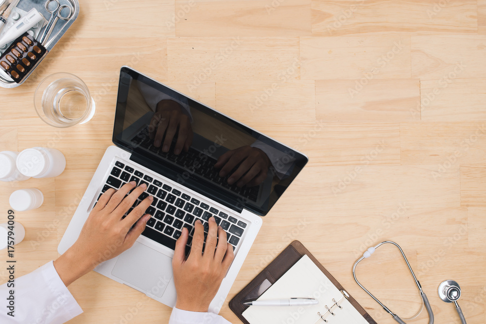 Doctor working on laptop computer and medical stethoscope on desk