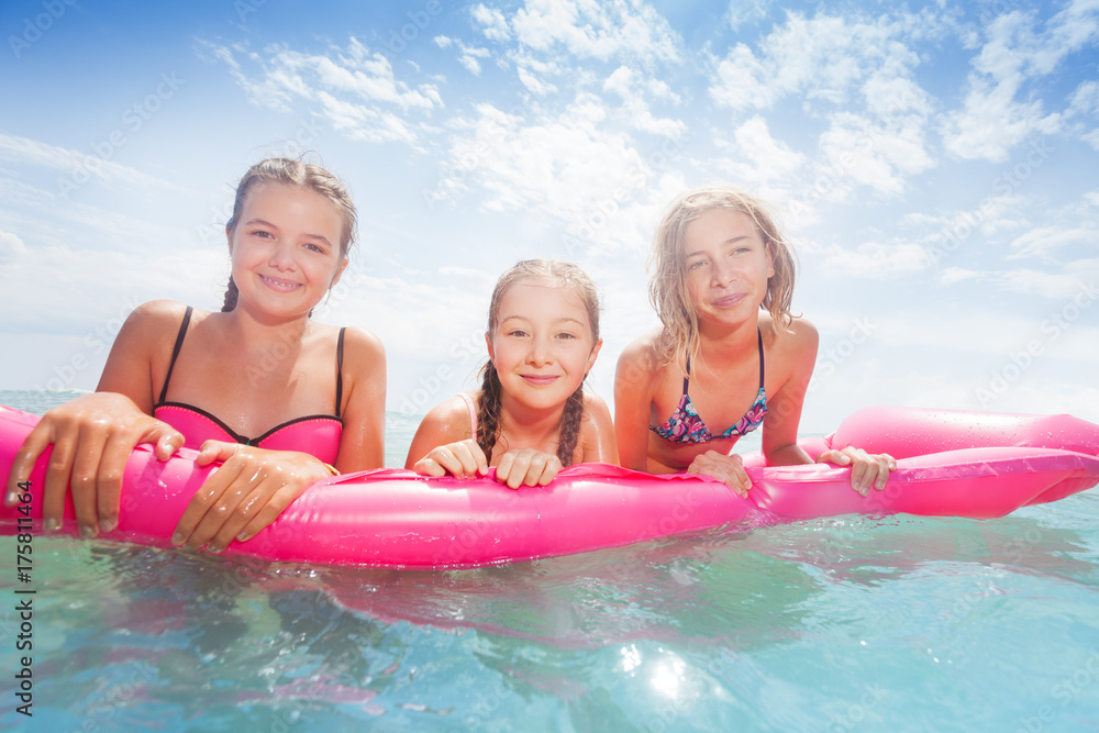 Group of girls on the pink matrass swim in sea