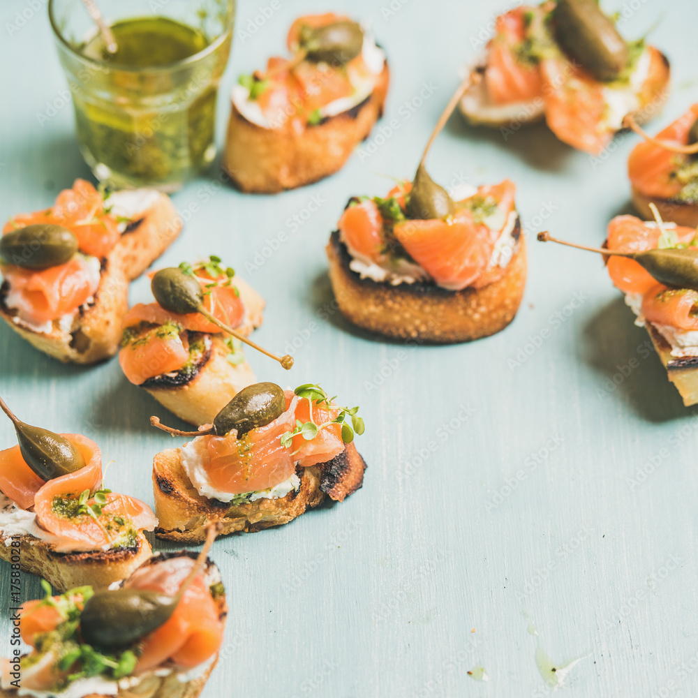 Crostini配烟熏三文鱼、香蒜酱、豆瓣菜和山柑，浅蓝色背景，精选