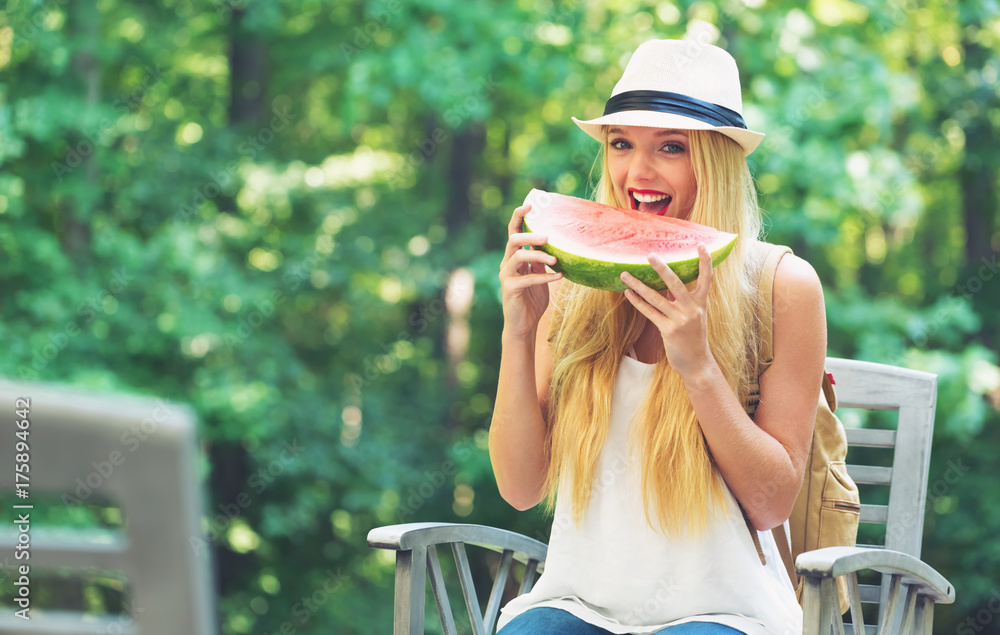 Young woman eating watermelon outside on a beautiful summer day