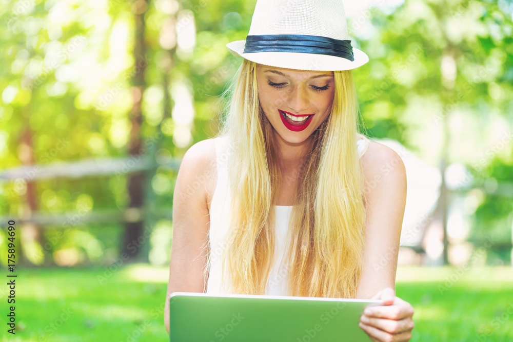 Young woman using her laptop outside on a beautiful summer day