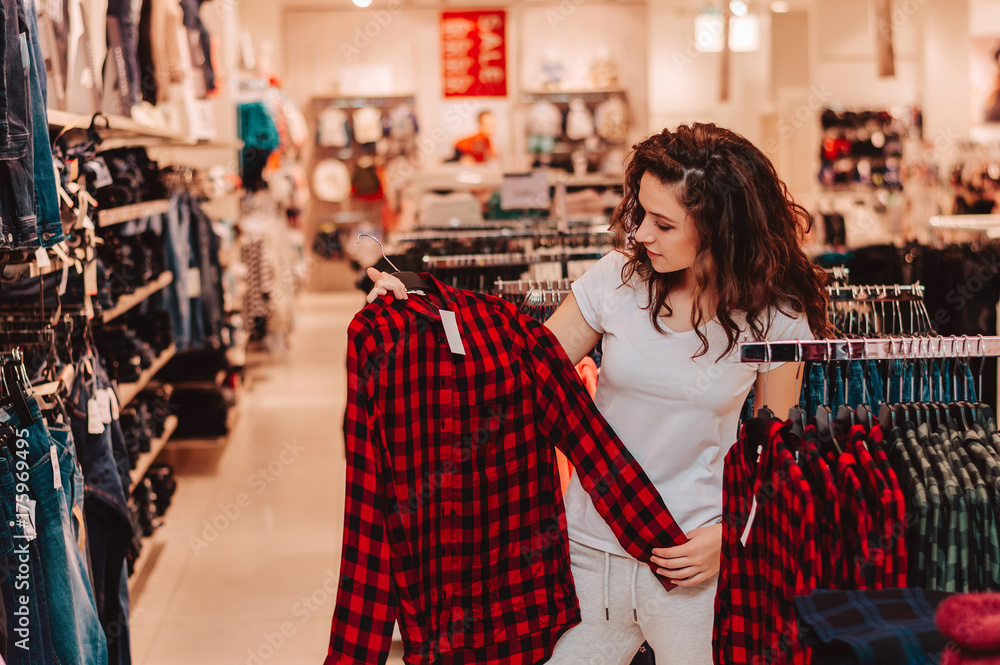 在店里挑选基本服装的深色女性顾客。