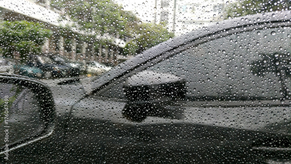 Rain drops on window with car background.