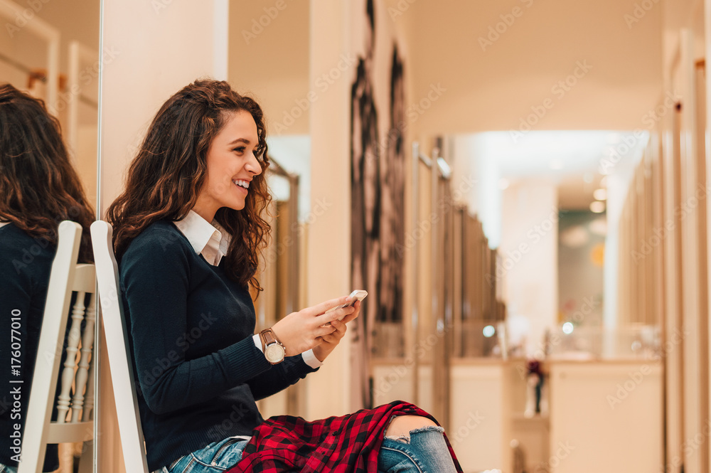 Attractive brunette using her phone in dressing room.