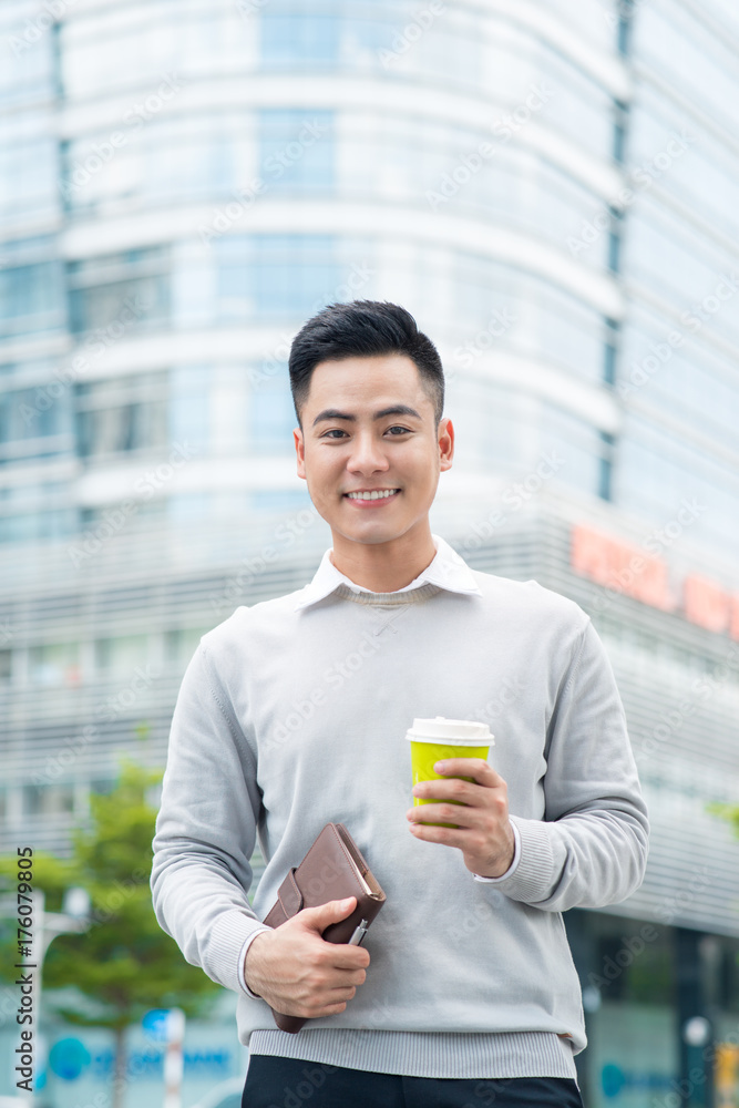 一个英俊的男人拿着咖啡站在城市街道上的肖像