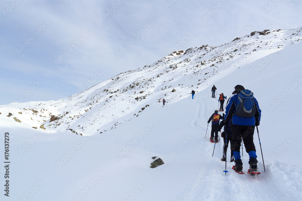 一群人穿着雪鞋徒步旅行，在奥地利斯塔拜阿尔卑斯山欣赏蓝天的山雪全景