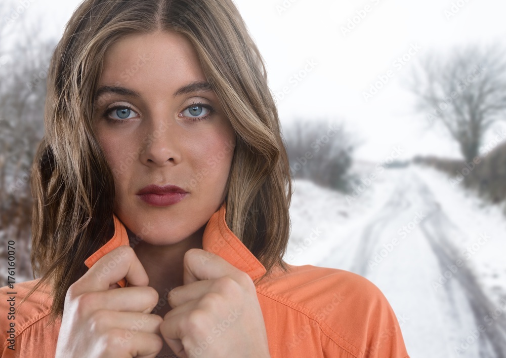 一名女子在雪地里紧紧抓住套头衫保暖