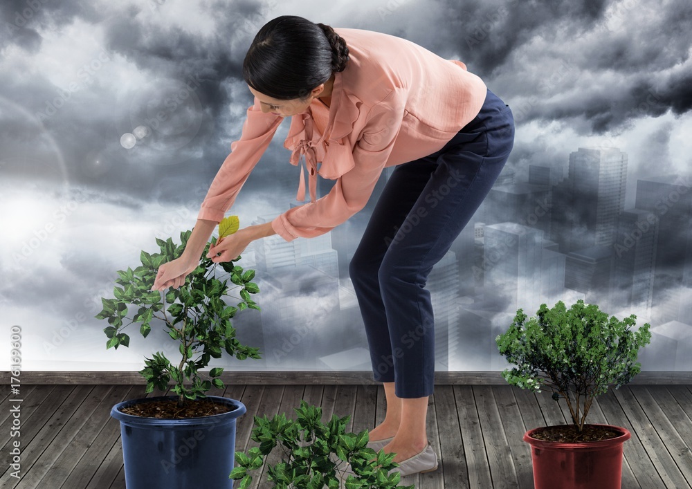 Businesswoman caring for plants gardening in city clouds