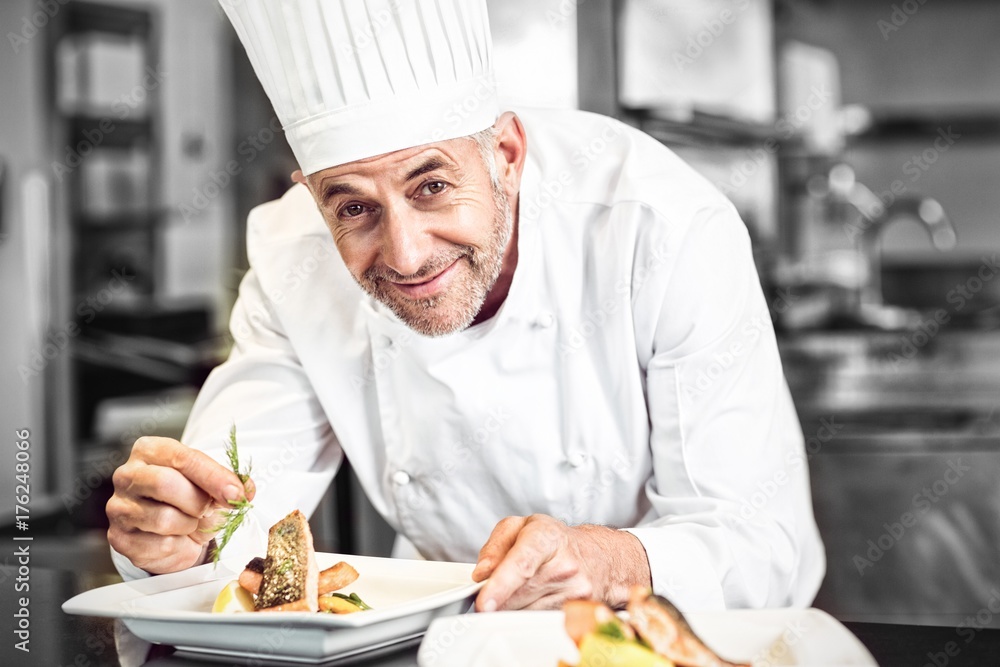 Smiling male chef garnishing food in kitchen