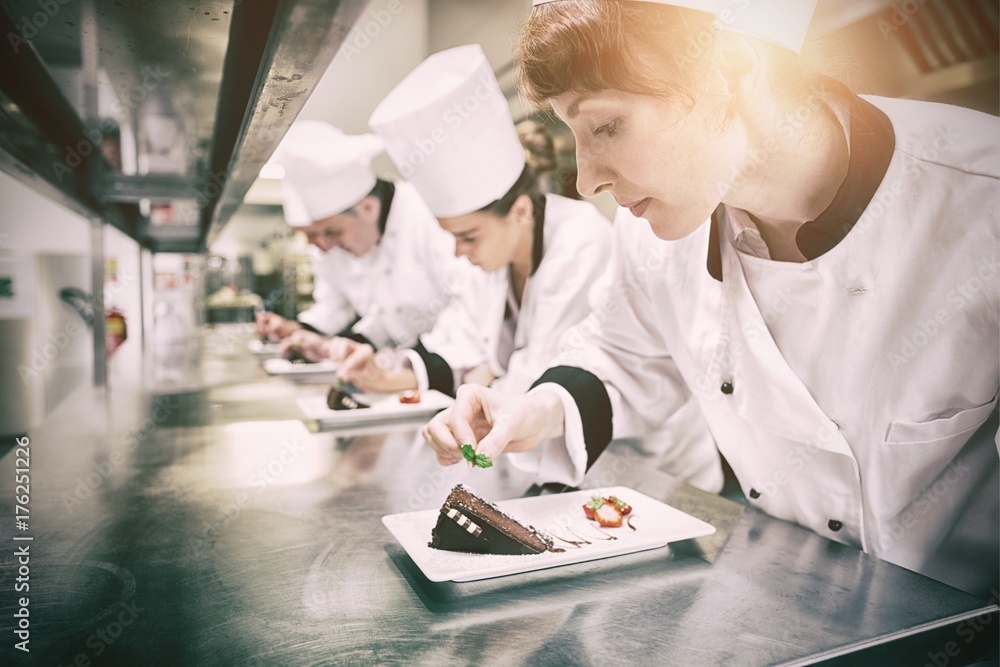 Chefs standing in a row garnishing dessert plates