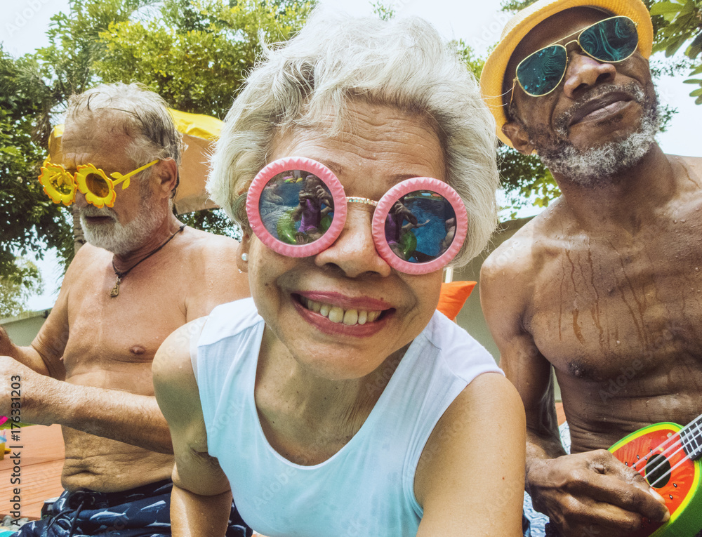 Closeup of diverse senior adults sitting by the pool enjoying summer together