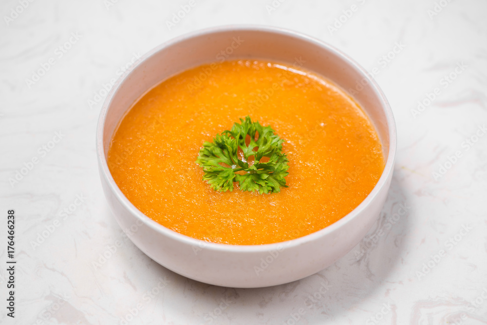 Carrot soup with cream and parsley on white stone background. Top view. Copy space