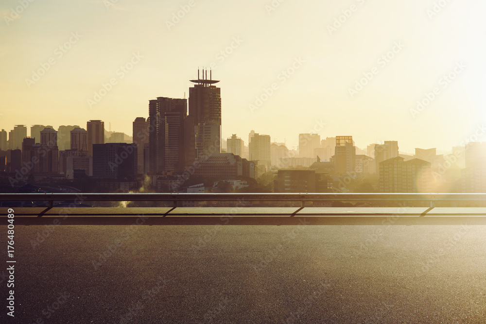 Empty asphalt road with city skyline background , sunrise or sunset scene .