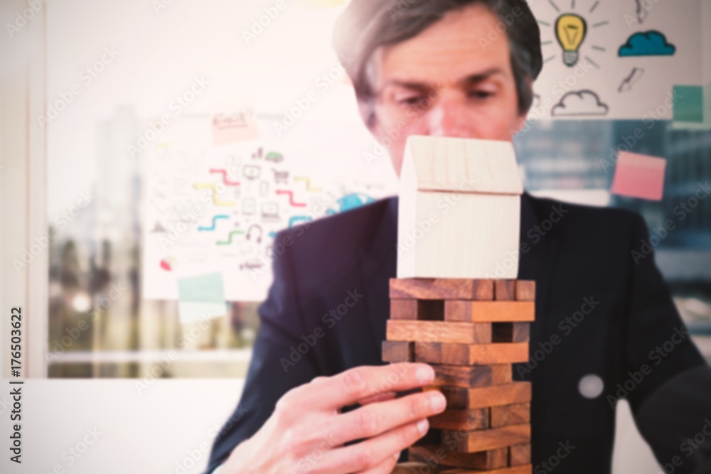 Composite image of businessman arranging wooden blocks at table