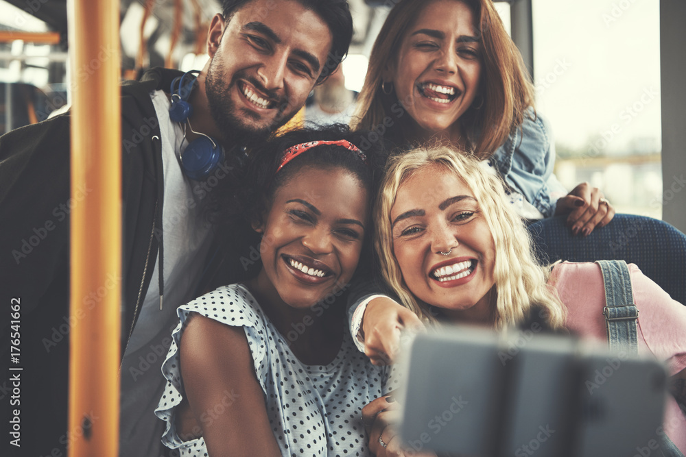 Smiling group of friends taking selfies together on a bus