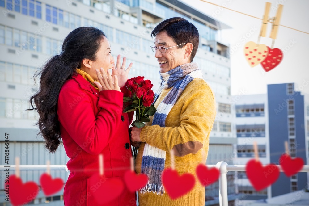 一对年长的亚洲夫妇在阳台上与玫瑰合影